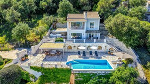 A two-story house with a swimming pool, stone walls, and outdoor seating. - Agios Stefanos Bay - Villa Maria (Agios Stefanos Kassiopi)