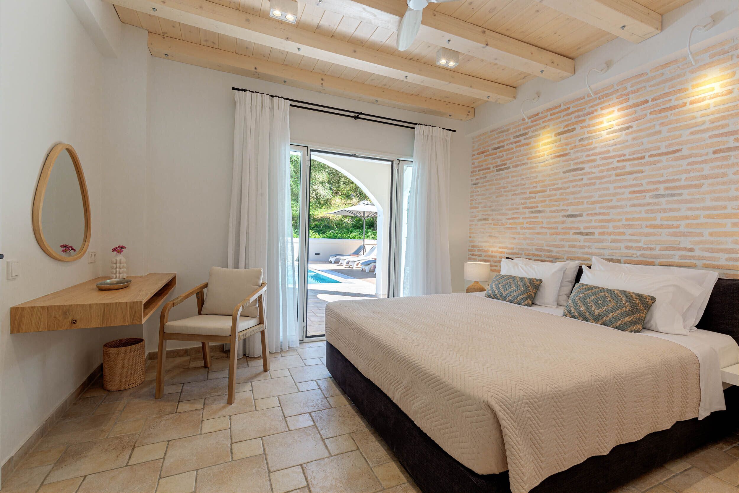 Ein Schlafzimmer mit Bett, Schreibtisch, Stuhl, Fenster und einer Ziegelwand.