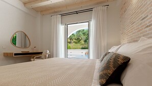Een slaapkamer met een groot bed, een houten hoofdbord, een spiegel, een nachtkastje en uitzicht op groen.