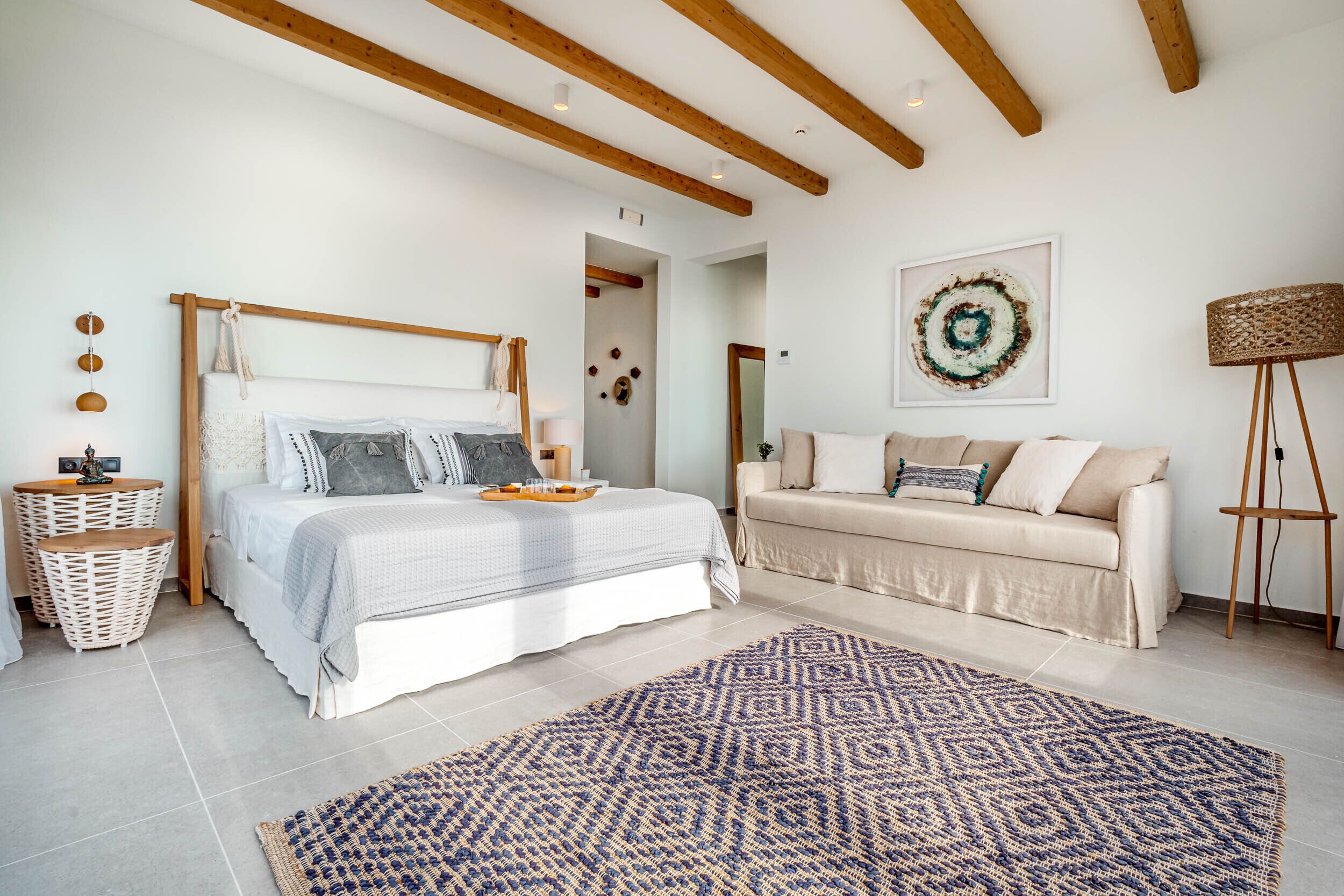 Ein Schlafzimmer mit einem Bett, einer Couch, einem gemusterten Teppich und einer Wand mit einer runden Dekoration.
