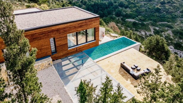 A modern house with a swimming pool, large windows, and a view of the sea.