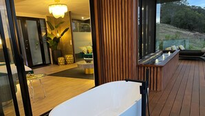 Une salle de bain moderne avec une baignoire sur pieds, un plancher en bois et une vue sur l’extérieur.