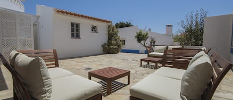 A patio with wooden furniture and a stone floor.