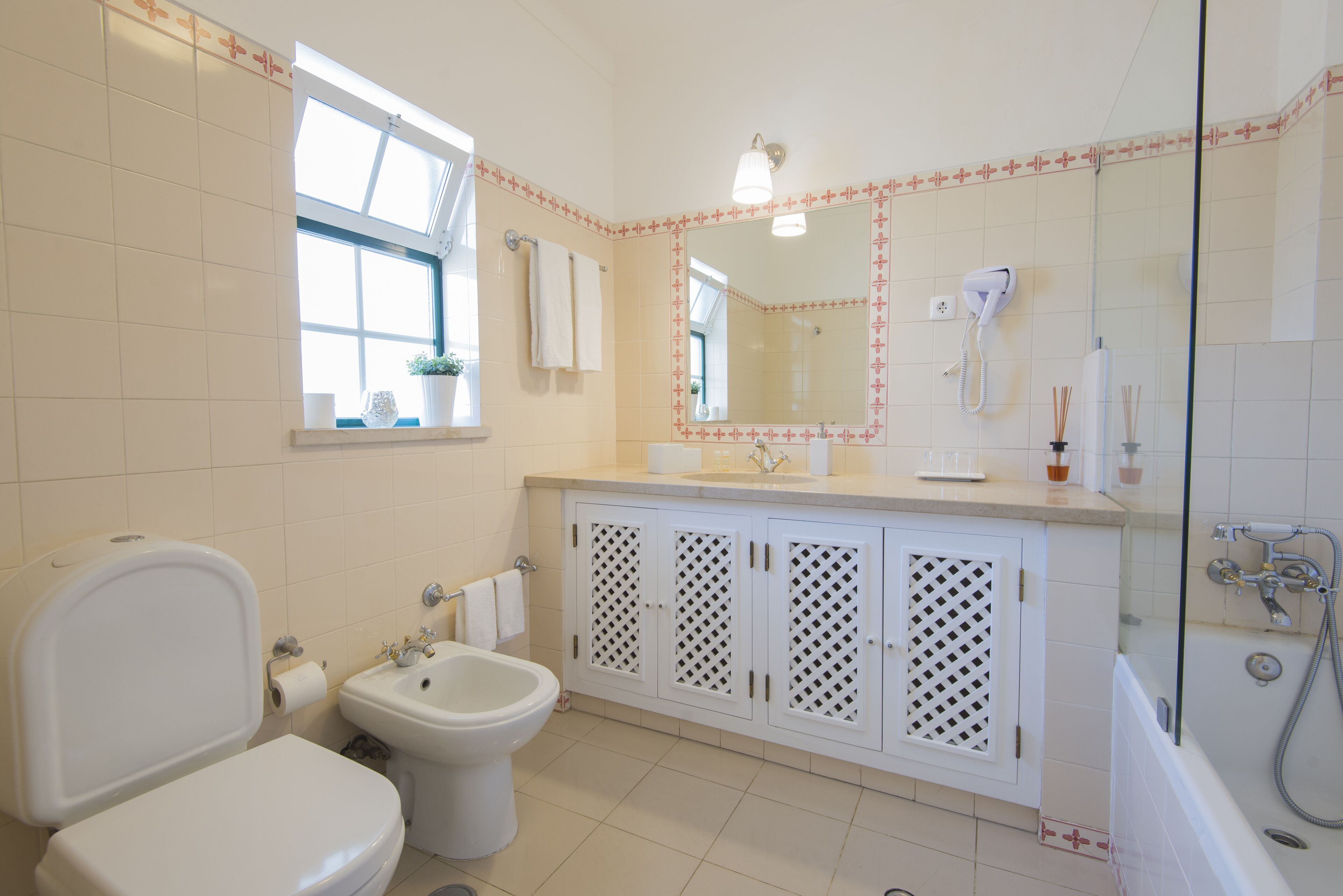 A bathroom with a toilet, bidet, sink, and shower.