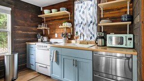 Une cuisine avec des murs en bois, un évier, une cuisinière et un four à micro-ondes.