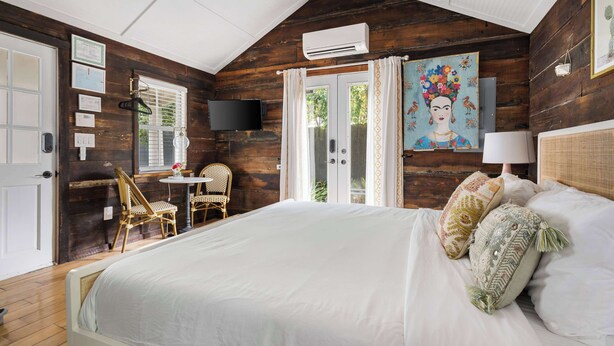 Une chambre à coucher avec un grand lit, une télévision, un bureau avec une chaise et une fenêtre avec des rideaux.