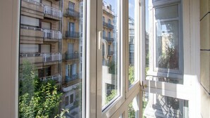 Blick durch ein Fenster eines Mehrstochergebäudes mit Balkonen, einer Tür und dem Spiegelbild eines anderen Gebäudes.