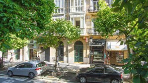 Straßenansicht eines Gebäudes mit Geschäften im Erdgeschoss und mehreren Balkonen.