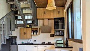 Une cuisine moderne avec un coin repas, un plafond en bois et un escalier.