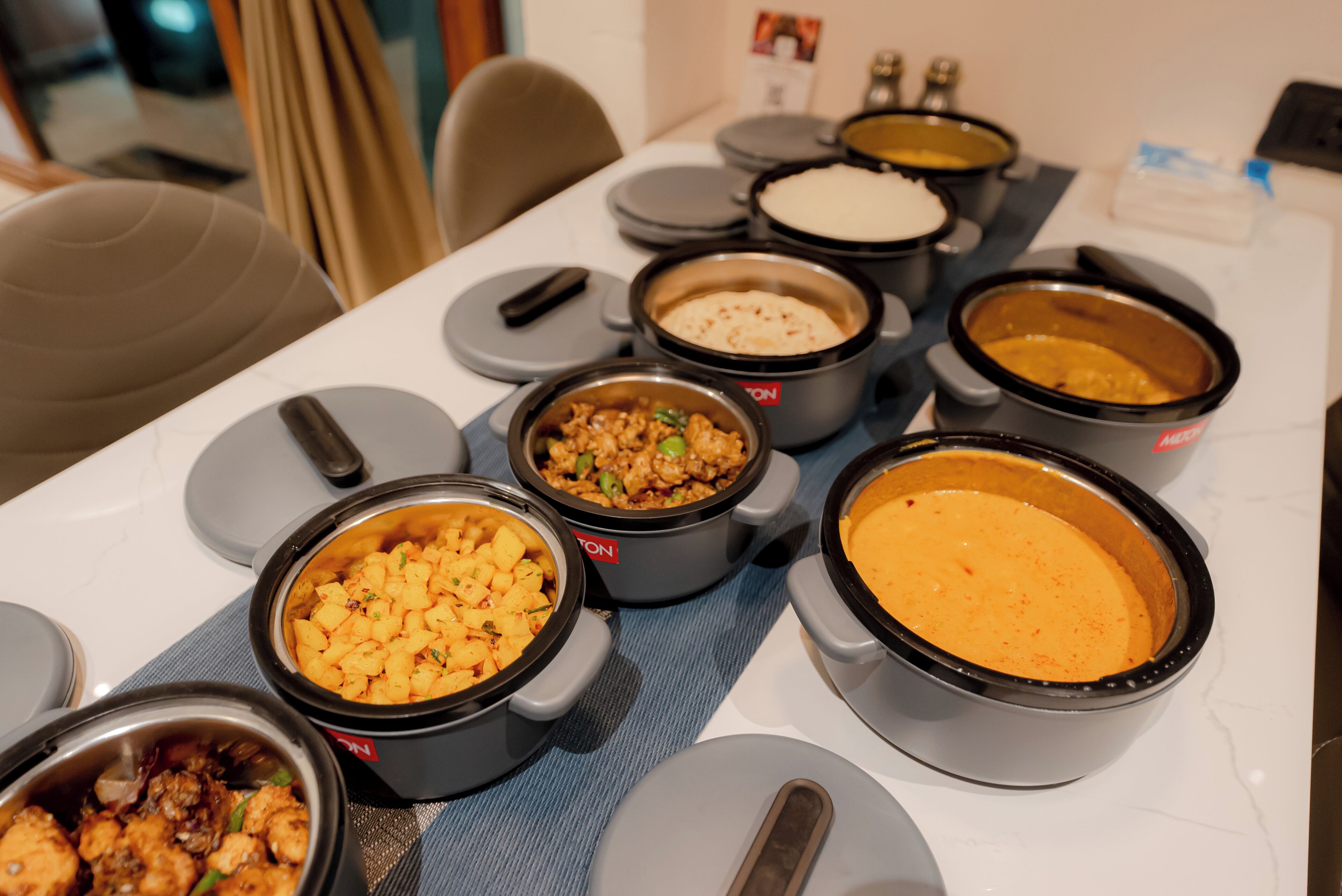 A table with multiple food containers, likely a buffet setup.