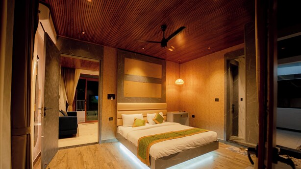 Une chambre moderne avec un grand lit, un ventilateur de plafond et une salle de bain visible.