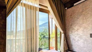 Une chambre avec un grand lit, une vue sur l’extérieur et un balcon.
