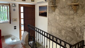 Un escalier avec un mur en pierre, une porte en bois et une vue sur l’extérieur.