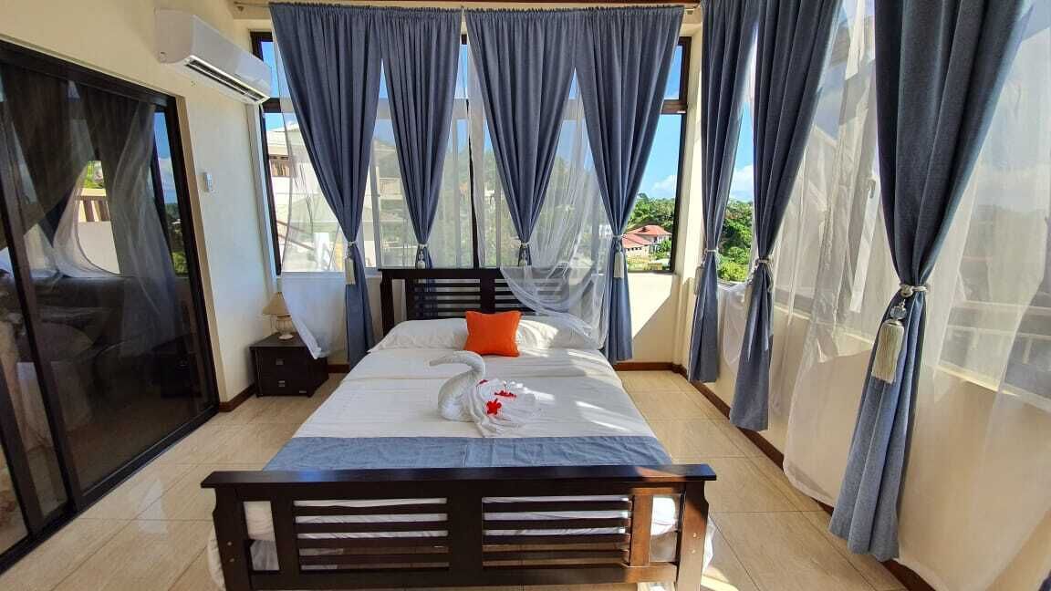 Ein Schlafzimmer mit Bett, Vorhängen und Blick ins Freie.