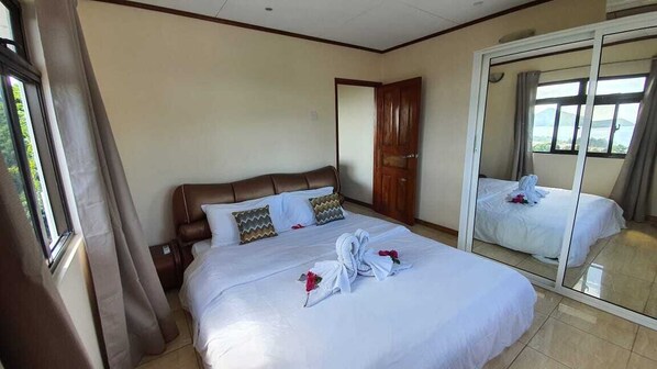 A hotel room with a large bed, a wardrobe, and a mirror reflecting the bed. - Maison L'Horizon (Mahé Island)