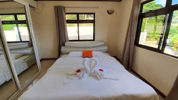 A hotel room with a bed, a sofa, a large window, and a mirror.