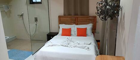 A hotel room with a bed, a wooden headboard, a shower, and a decorative wall piece.