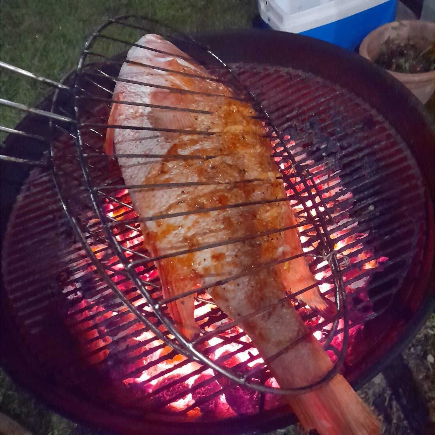 Een gegrilde vis op een grill, met duidelijke grillstrepen.