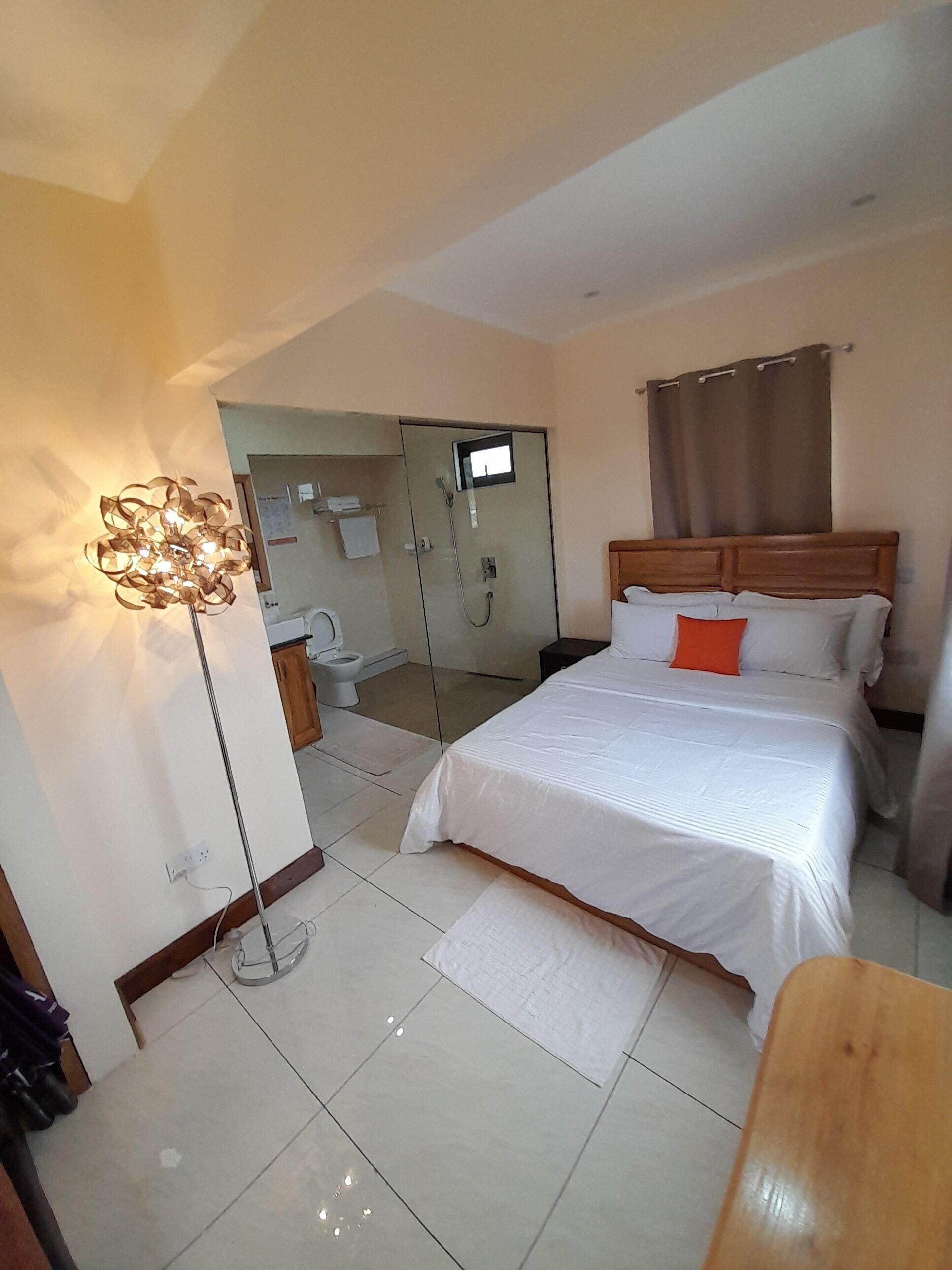 A bedroom with a bed, a bedside table, a mirror, a wardrobe, and a floor lamp.