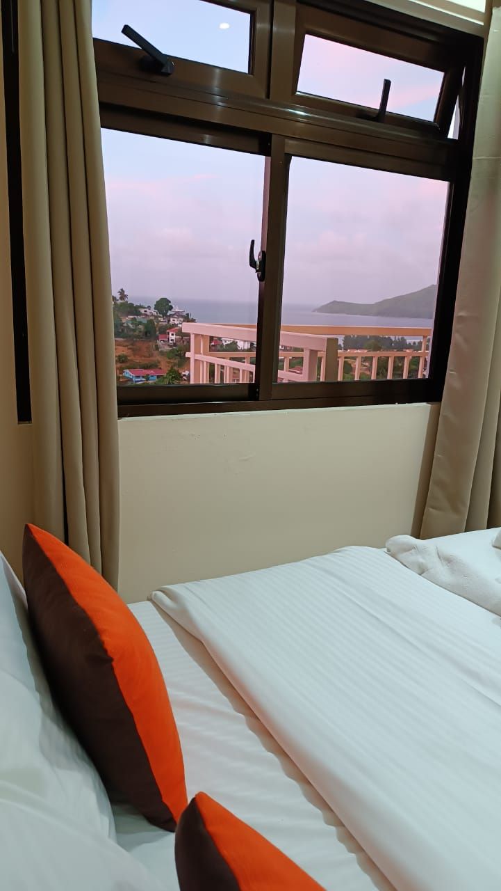 Ein Hotelzimmer mit Bett, einem Fenster mit Blick auf Gebäude und ein Gewässer, sowie Vorhängen.