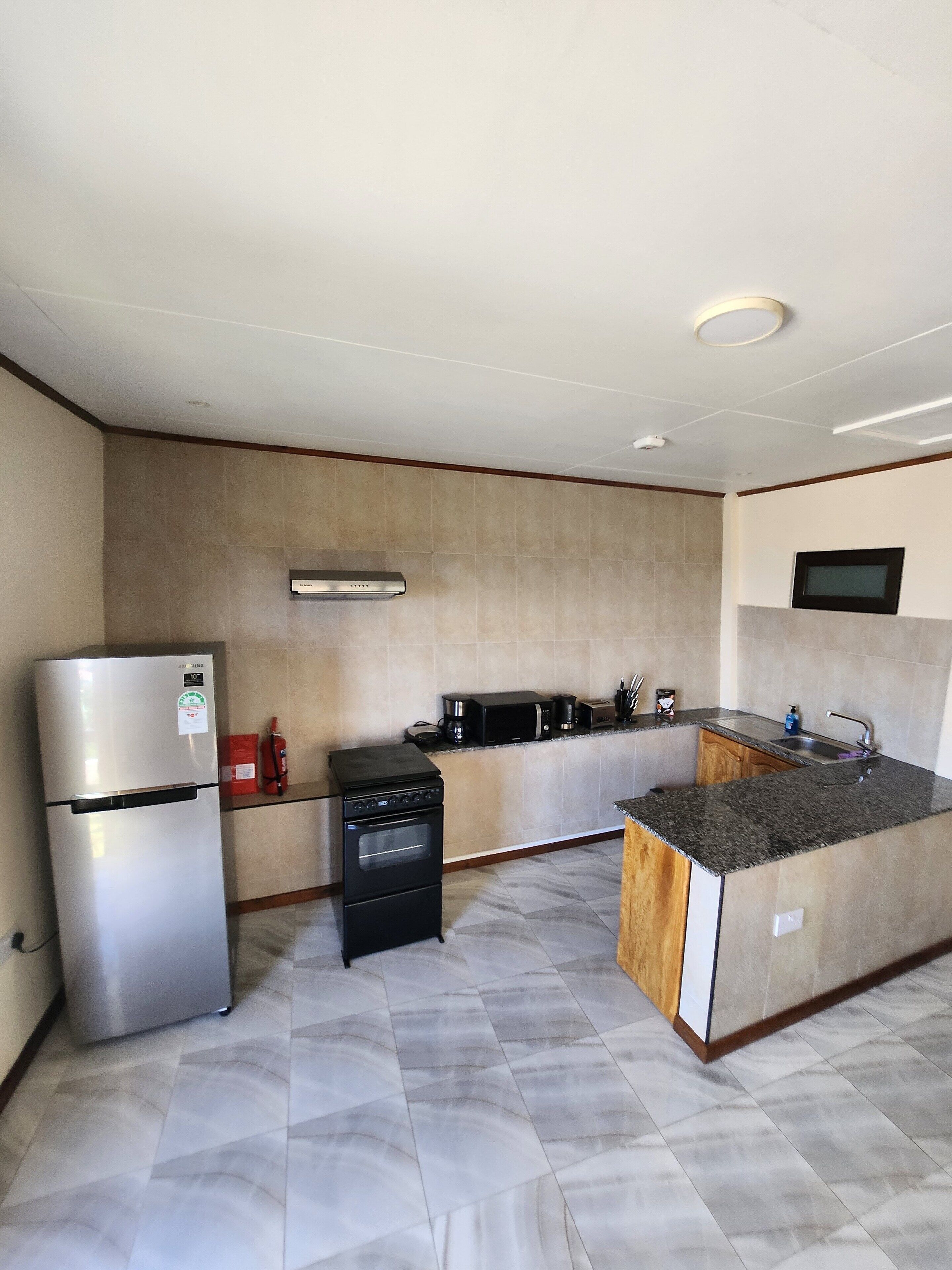 A modern kitchen with a stainless steel refrigerator, a black stove, and a microwave.