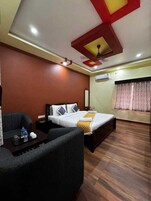 Habitación de hotel con cama, sofá, una mesita con bandeja y un equipo de aire acondicionado.