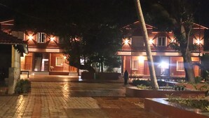 A building with a tiled entrance and a paved pathway leading to a gated area. - Aashrayam Hotels And Resorts (Honavar)