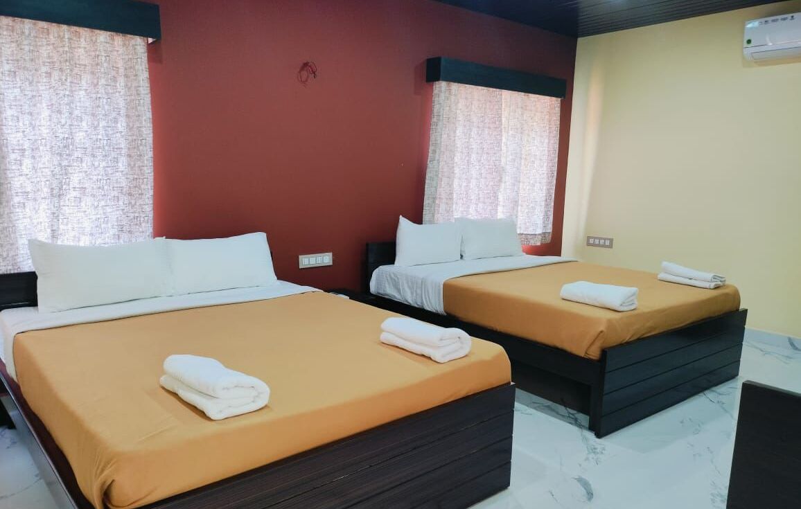 Ein Hotelzimmer mit zwei Betten, jedes mit einem weißen Kopfkissen und einem gefalteten Handtuch.
