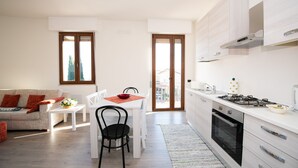 Une cuisine moderne avec des meubles blancs, une cuisinière à gaz et un coin repas comprenant une table et des chaises blanches.