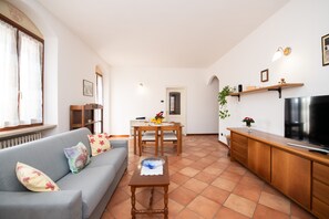 A living room with a sofa, a coffee table, a TV, and a dining area with a table and chairs.