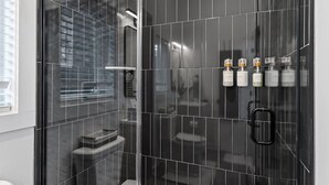 A modern bathroom with a glass-enclosed shower, a toilet, and a sink. - Chic Downtown Raleigh Tiny House (Raleigh)