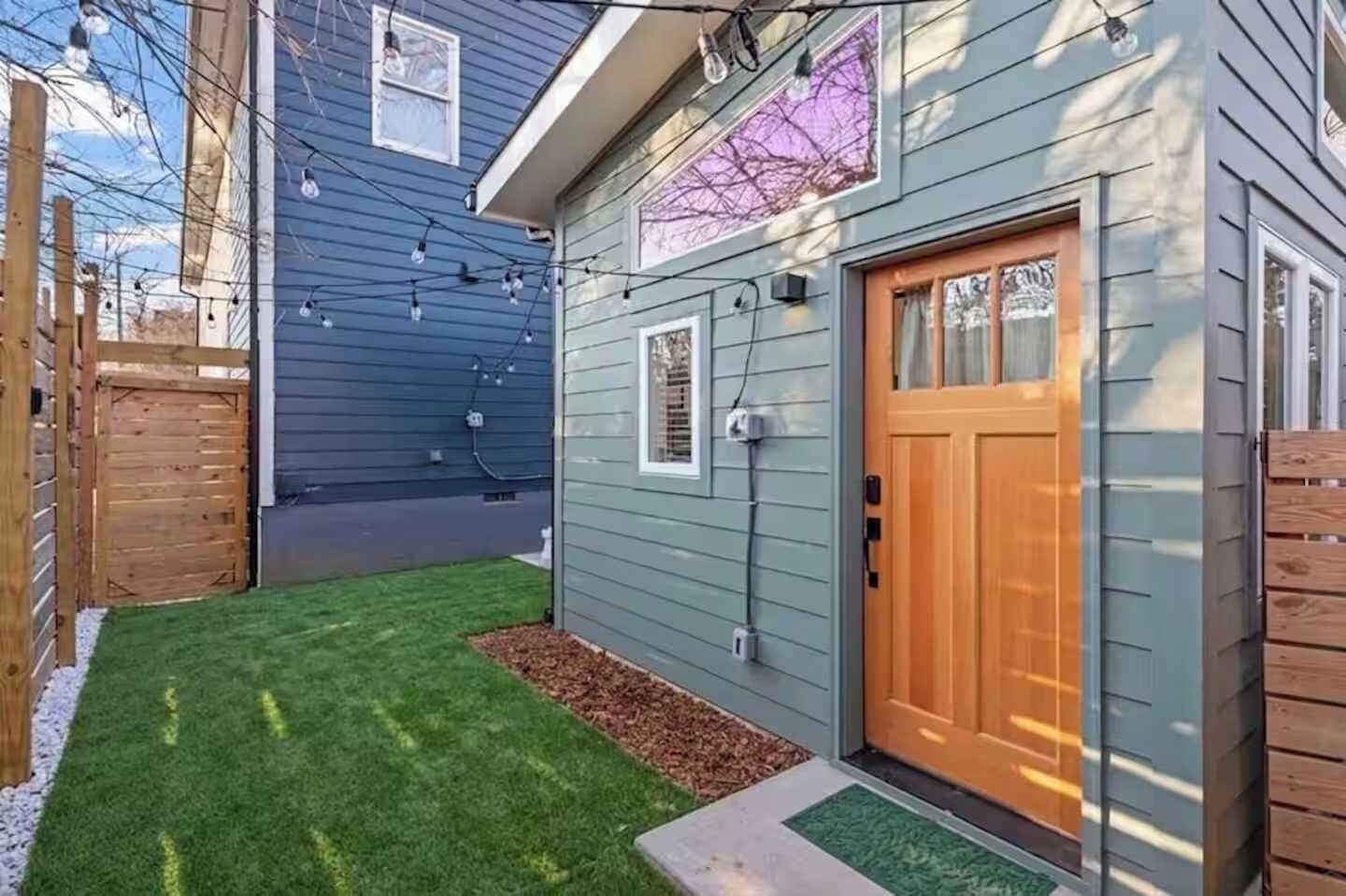 A residential property with a wooden door, a small lawn, and a light blue exterior.