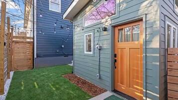 A residential property with a wooden door, a small lawn, and a light blue exterior.