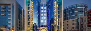 Un hotel moderno con un atrio central, varios pisos y una fachada de vidrio curvo.