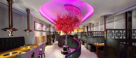 A modern interior with a central spiral staircase, seating areas, and a decorative tree.