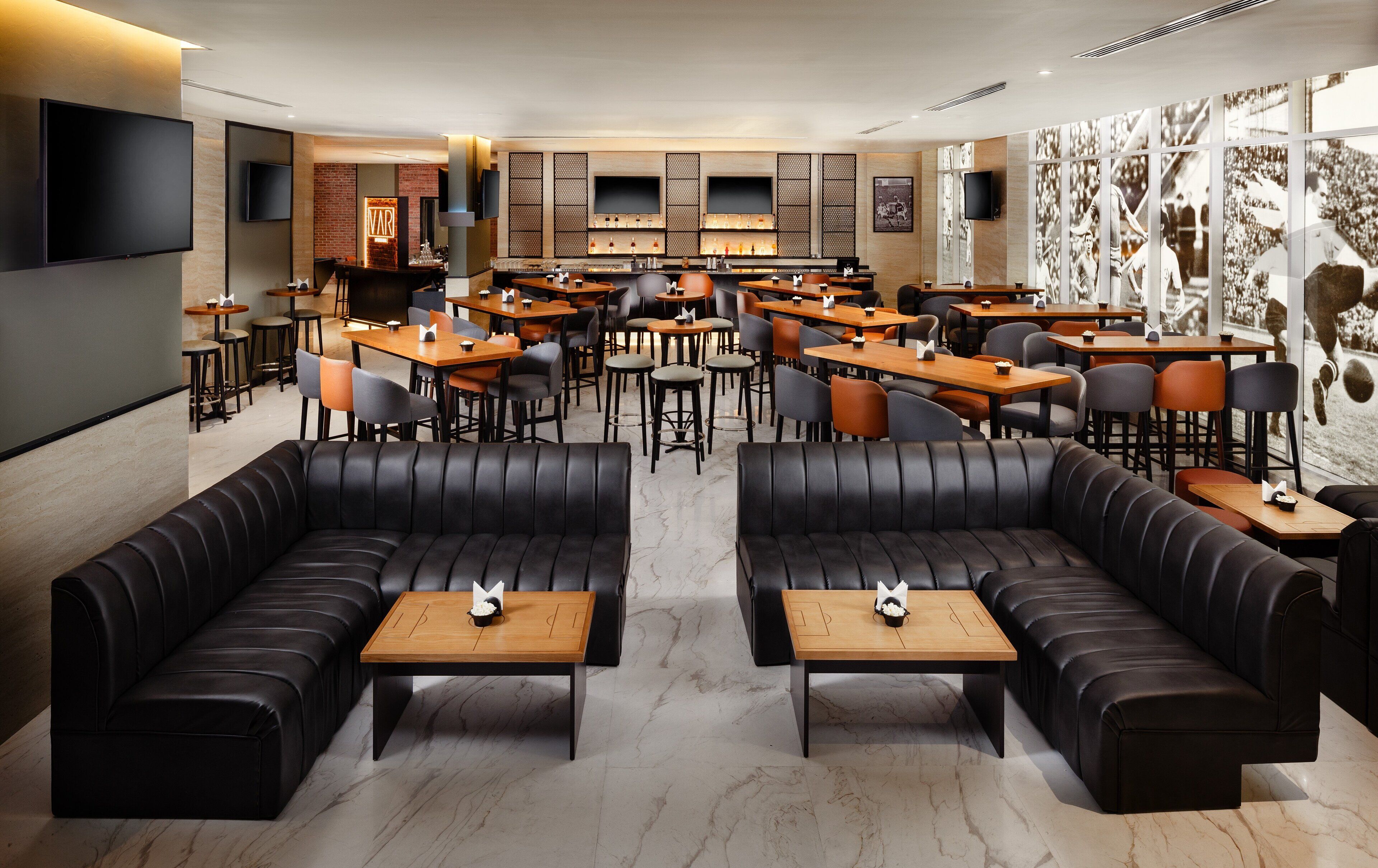 Un restaurante moderno con sofás de cuero, mesas de madera y una zona de bar.