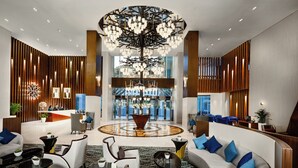 A spacious lobby with a central chandelier, seating areas, and a reception desk. - Millennium Place Doha (Doha)