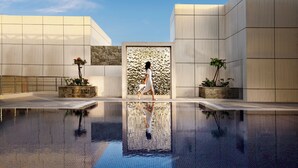 A modern building with a reflective pool, stone walls, and potted plants. - Millennium Place Doha (Doha)