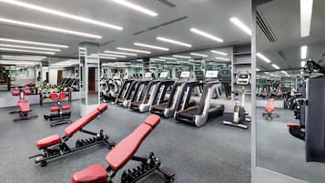 A modern gym with treadmills, weight machines, and benches.