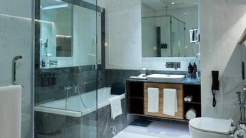 A modern bathroom with a glass-enclosed shower, a white bathtub, a vanity with a sink, and a toilet.