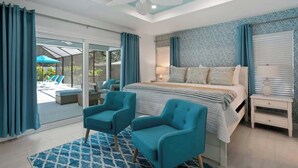A bedroom with a large bed, two armchairs, a nightstand, and a ceiling fan. - 2 Homes, 2 Pools, 2 Game Rooms, Sleeps 21 | IMG (Bradenton)