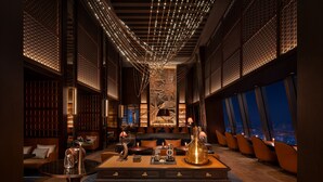 A luxurious interior with a central table, seating area, and a city view through large windows. - Four Seasons Hotel Dalian (Dalian)