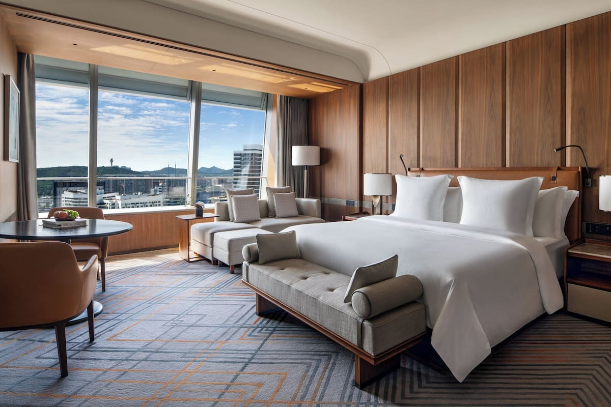 Habitación de hotel moderna con una cama grande, un sofá, un escritorio y vistas a la ciudad.
