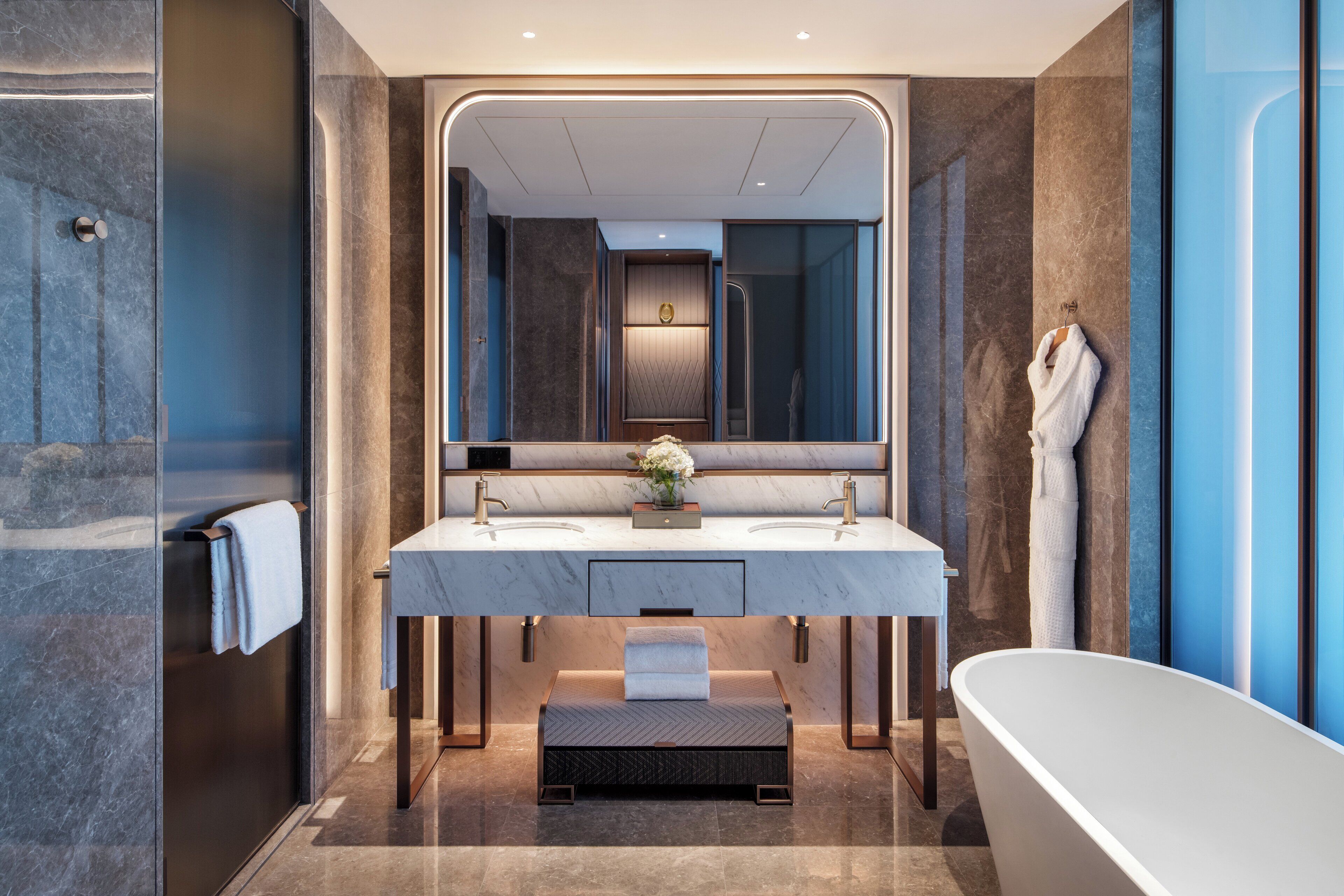 Un baño moderno con un espejo grande, dos lavamanos, una bañera y un perchero para toallas.