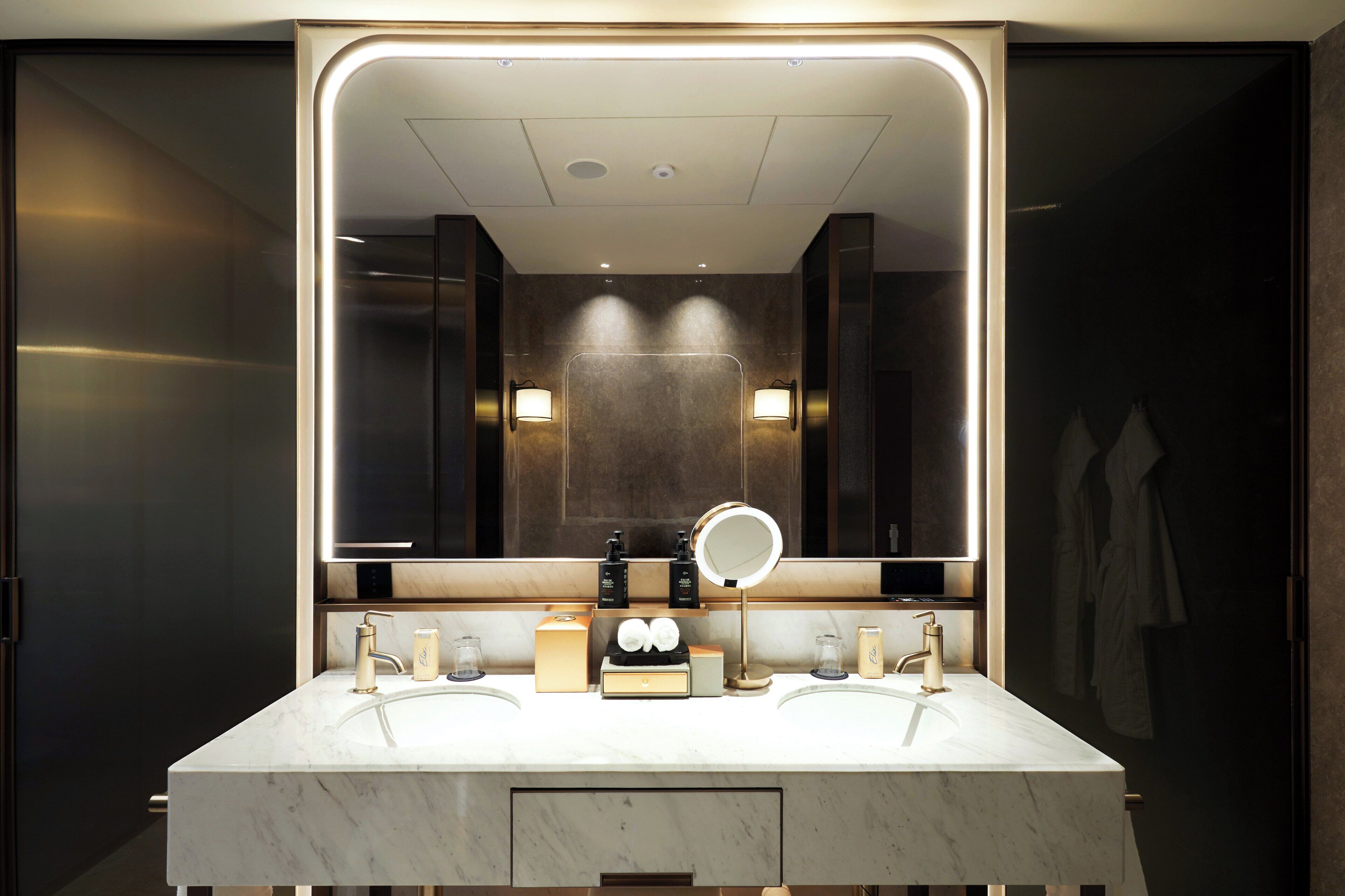 Un baño moderno con un espejo grande, dos lavamanos y un mueble de tocador.