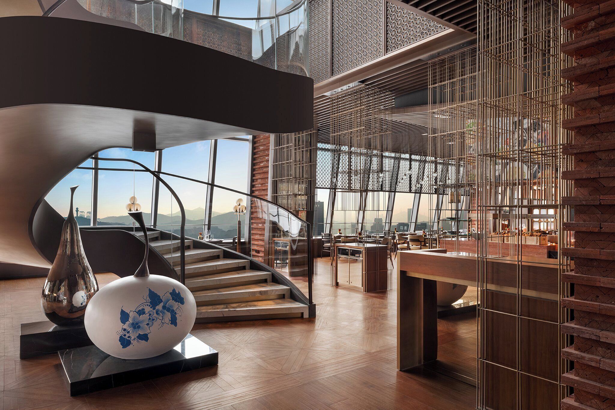 Un interior moderno con una escalera, un ventanal grande y un jarrón decorativo.