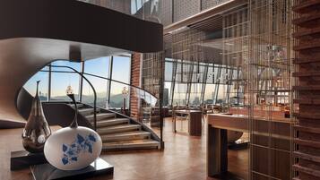 Un interior moderno con una escalera, un ventanal grande y un jarrón decorativo.