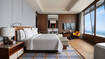 A modern hotel room with a large bed, a desk, a chair, and a TV.