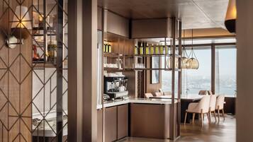 A modern kitchen with a built-in espresso machine, a dining area with a view, and a bar area with bottles.