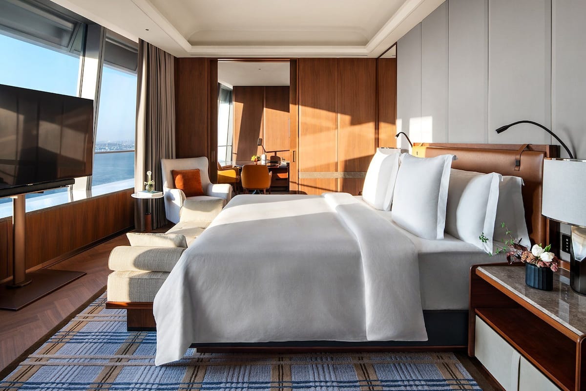 Habitación de hotel moderna con una cama grande, televisor, escritorio y vistas a la ciudad.